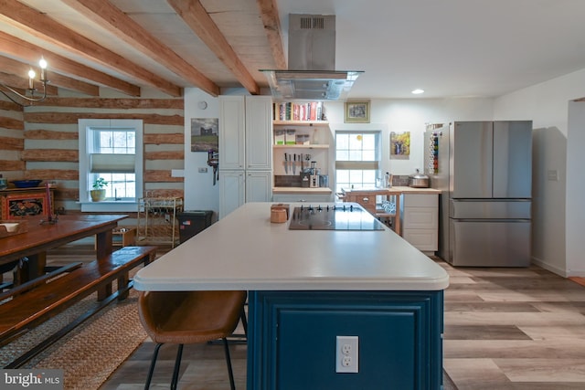 kitchen featuring freestanding refrigerator, island exhaust hood, black electric stovetop, light countertops, and light wood-type flooring