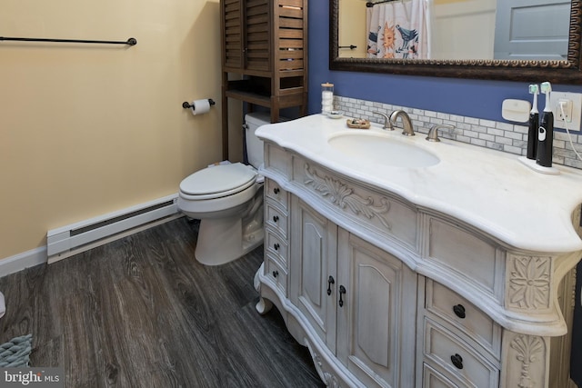 bathroom with a baseboard radiator, toilet, wood finished floors, vanity, and decorative backsplash