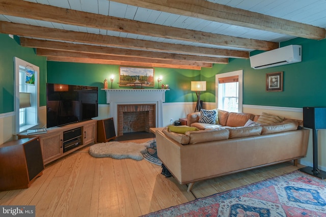 living room featuring beam ceiling, a fireplace, wood-type flooring, a wall mounted AC, and wainscoting