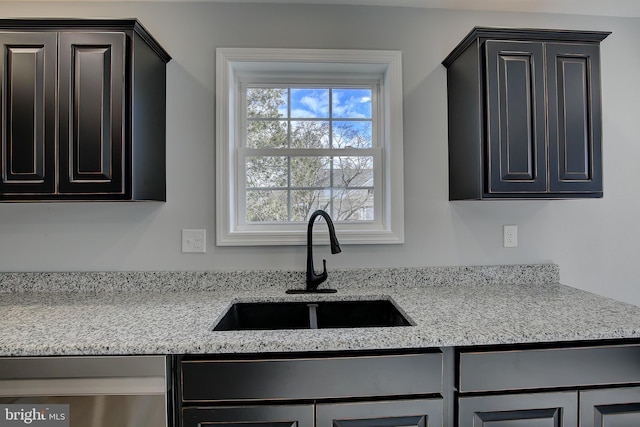 kitchen with light stone counters, sink, and stainless steel dishwasher