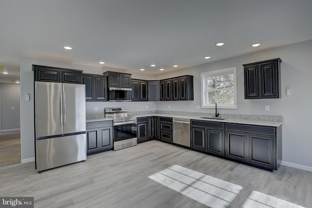 kitchen featuring light stone counters, sink, stainless steel appliances, and light wood-type flooring