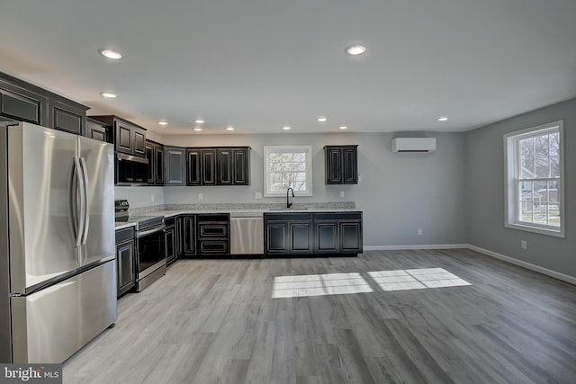 kitchen featuring sink, a wall unit AC, dark brown cabinets, appliances with stainless steel finishes, and light wood-type flooring