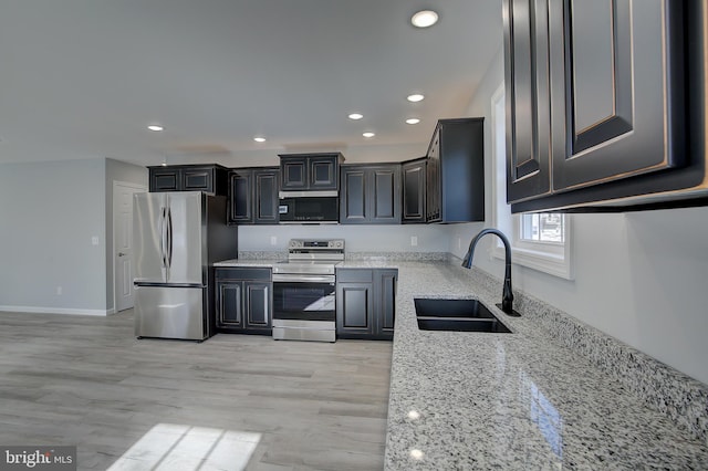 kitchen with light hardwood / wood-style flooring, stainless steel appliances, light stone counters, and sink