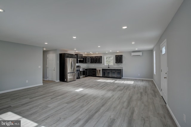 unfurnished living room featuring light wood-type flooring, a wall unit AC, and sink