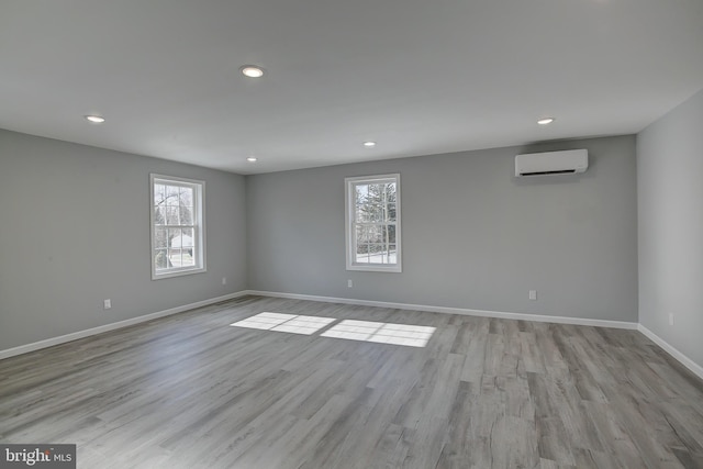 spare room featuring a wall unit AC and light hardwood / wood-style floors