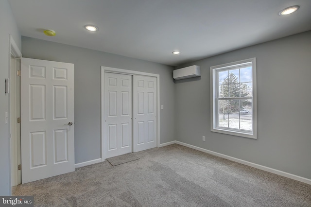 unfurnished bedroom featuring a wall unit AC, a closet, and light colored carpet