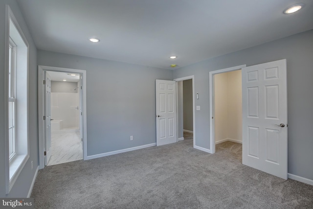 unfurnished bedroom featuring ensuite bath and light colored carpet