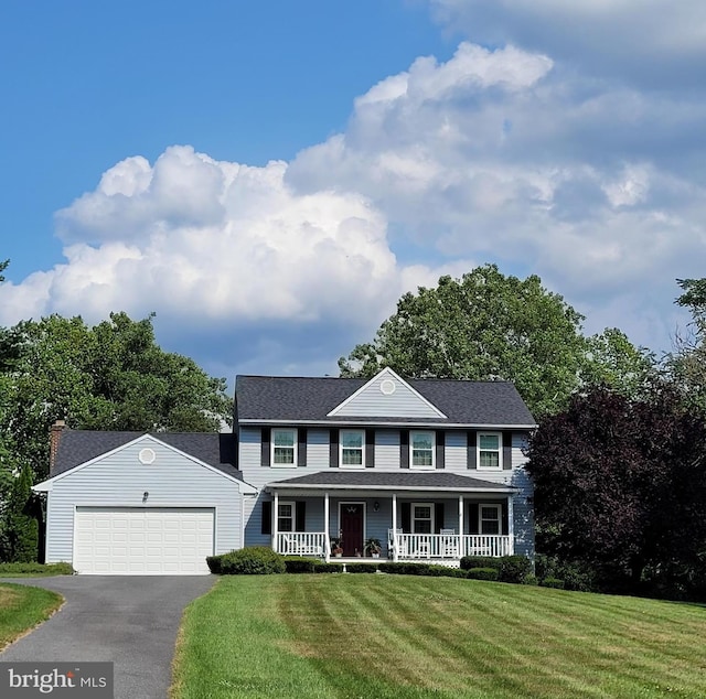 colonial home featuring a porch, a garage, and a front yard