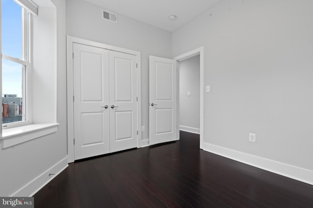 unfurnished bedroom featuring dark wood-type flooring and a closet