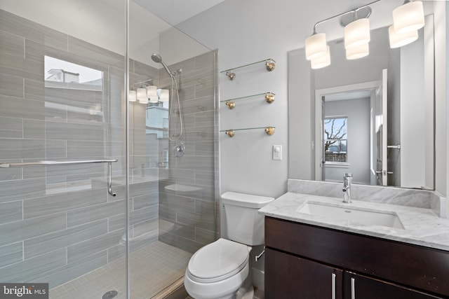 bathroom featuring toilet, vanity, and a shower with door