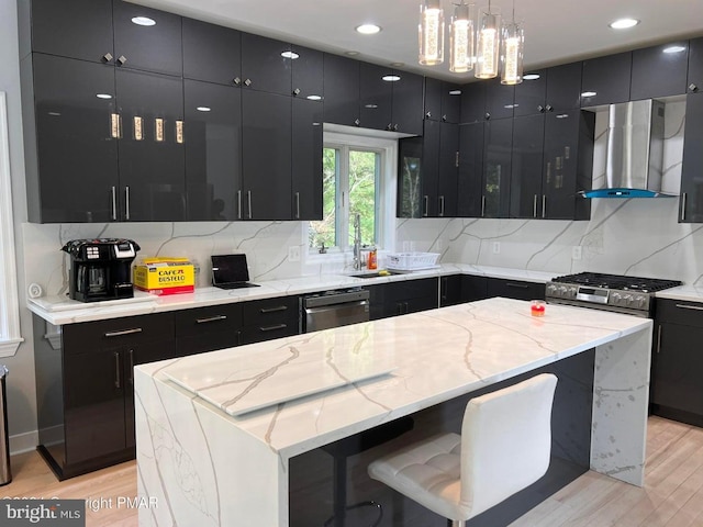 kitchen with wall chimney exhaust hood, a kitchen island, hanging light fixtures, and appliances with stainless steel finishes