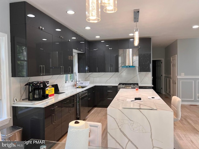 kitchen with pendant lighting, sink, light hardwood / wood-style flooring, and wall chimney range hood