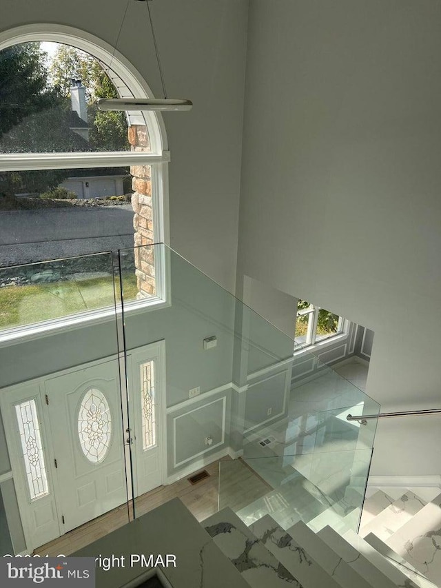 foyer with a towering ceiling, a wealth of natural light, and light tile patterned flooring