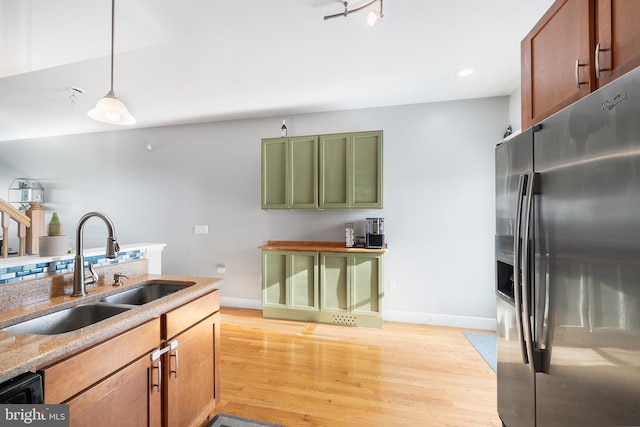 kitchen with decorative light fixtures, sink, green cabinets, stainless steel refrigerator with ice dispenser, and light wood-type flooring