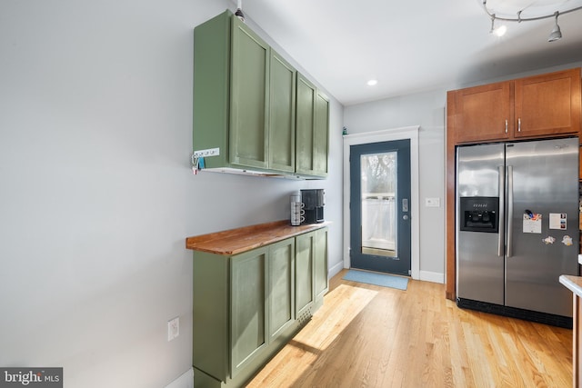 kitchen featuring butcher block counters, light wood-type flooring, green cabinetry, and stainless steel refrigerator with ice dispenser