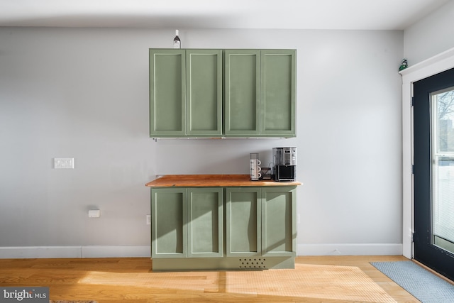 bar featuring green cabinetry, butcher block counters, and light hardwood / wood-style floors