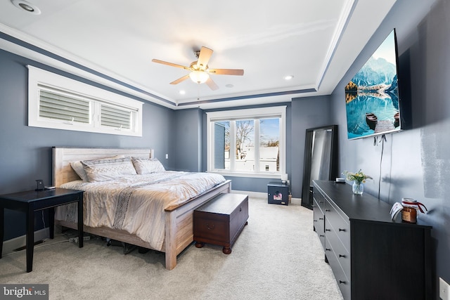 bedroom with light colored carpet, a raised ceiling, and ceiling fan