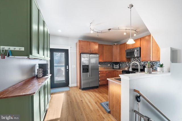 kitchen featuring decorative light fixtures, sink, decorative backsplash, stainless steel appliances, and light hardwood / wood-style flooring