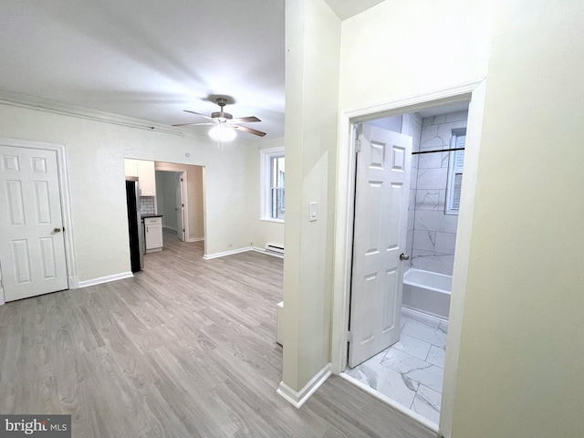 corridor with light hardwood / wood-style flooring and a baseboard heating unit