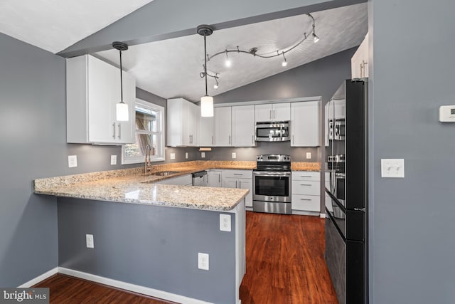 kitchen featuring vaulted ceiling, white cabinets, pendant lighting, and appliances with stainless steel finishes