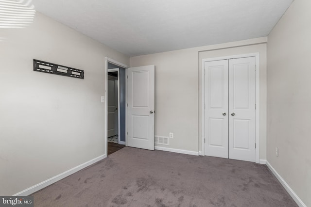 unfurnished bedroom with dark carpet and a closet