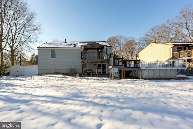 snow covered back of property featuring a deck