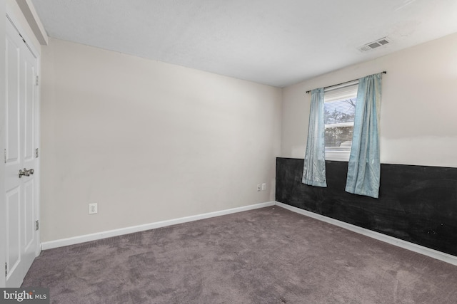 spare room featuring dark colored carpet