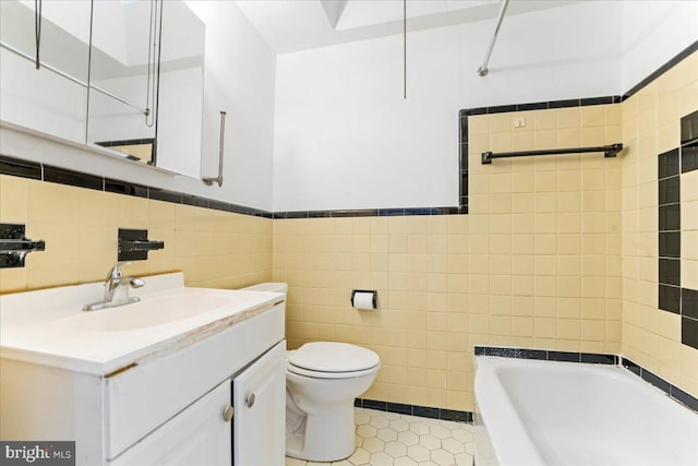 bathroom with toilet, tile patterned flooring, tile walls, a bath, and vanity