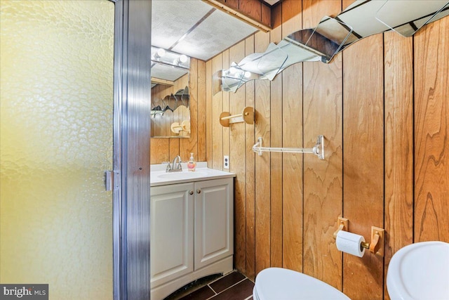 bathroom featuring wood walls, vanity, and toilet