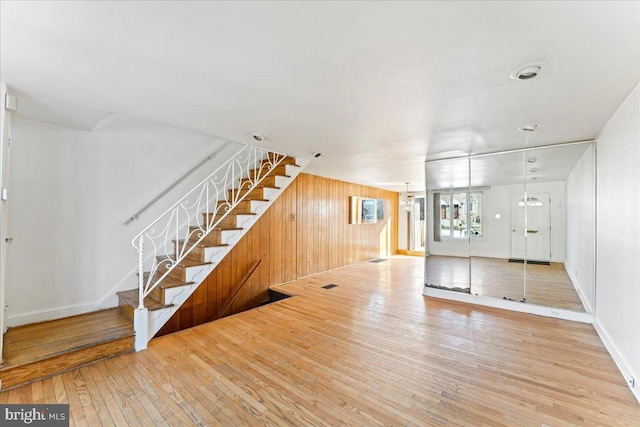 unfurnished living room with light wood-type flooring and wooden walls