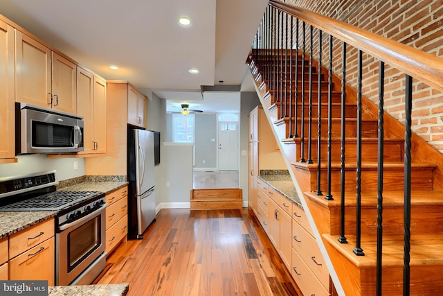 kitchen with light brown cabinets, light stone counters, and stainless steel appliances