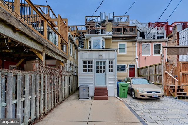 back of house featuring entry steps, fence, and central AC