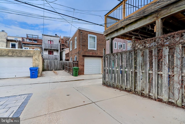 view of patio featuring a garage, concrete driveway, and fence