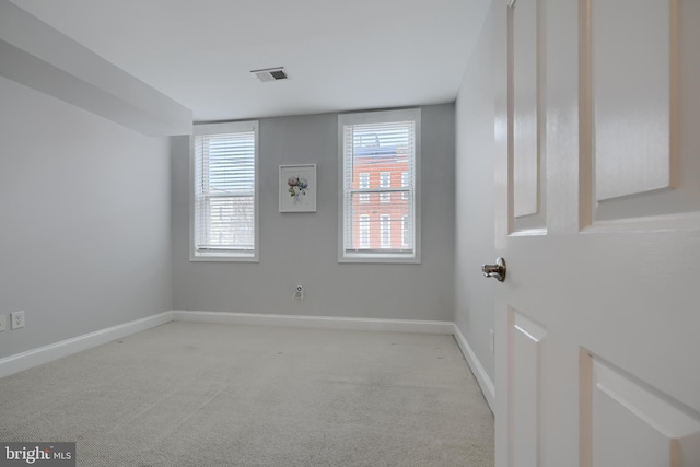 spare room with baseboards, visible vents, and light colored carpet