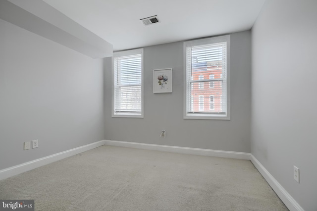 spare room with light carpet, visible vents, and baseboards