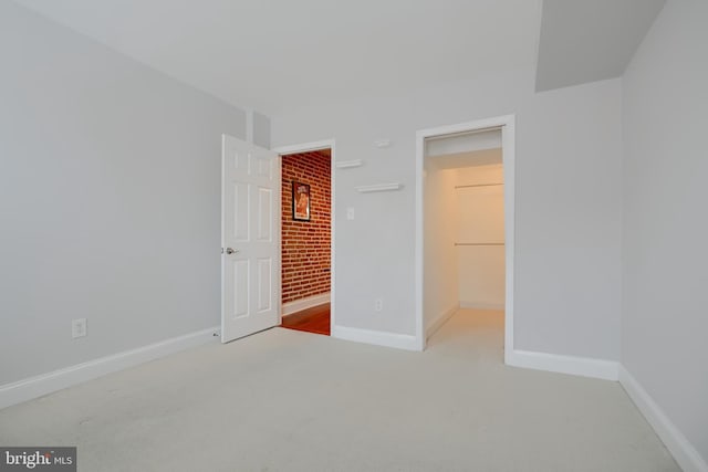 unfurnished bedroom featuring carpet, a closet, a spacious closet, and baseboards