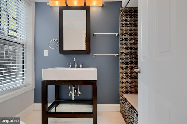 full bathroom featuring a healthy amount of sunlight, tile patterned flooring, baseboards, and a sink