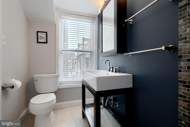 half bathroom featuring toilet, tile patterned flooring, baseboards, and vanity