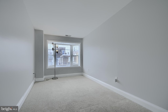 carpeted spare room with visible vents and baseboards