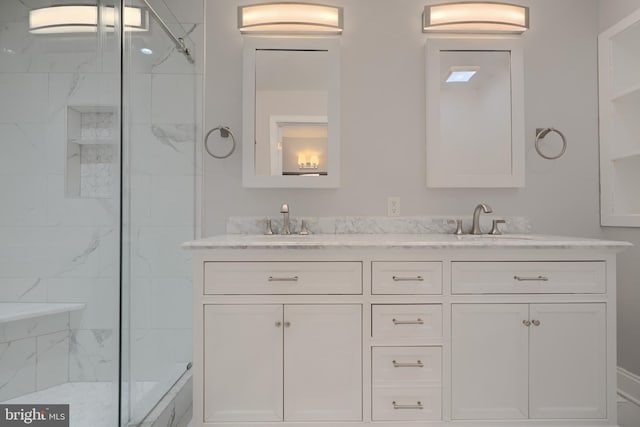 full bath with a sink, double vanity, and a marble finish shower