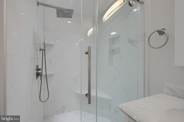 full bathroom featuring a marble finish shower and vanity