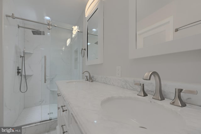 bathroom with double vanity, a sink, and a marble finish shower