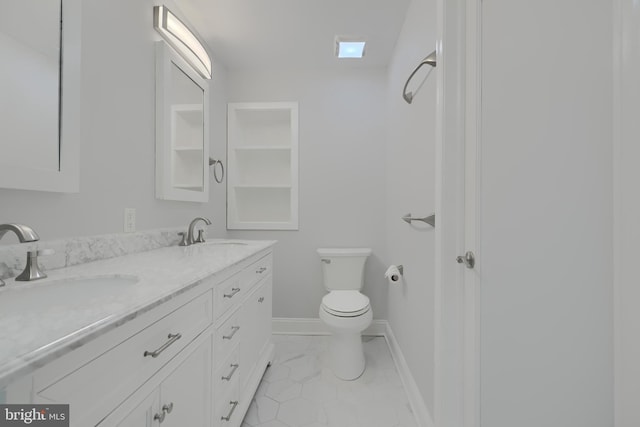 bathroom with double vanity, a sink, toilet, and baseboards