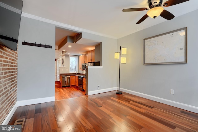 unfurnished living room with a ceiling fan, baseboards, visible vents, light wood finished floors, and crown molding