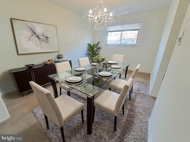 dining space with light hardwood / wood-style flooring and a chandelier