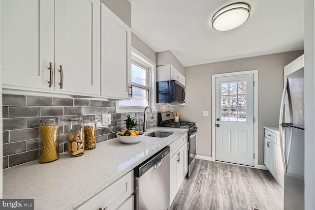 kitchen with appliances with stainless steel finishes, white cabinets, backsplash, and plenty of natural light