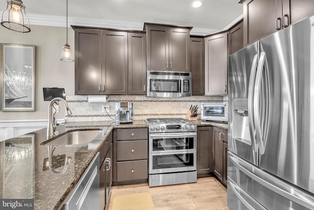 kitchen with sink, dark stone countertops, hanging light fixtures, dark brown cabinetry, and stainless steel appliances