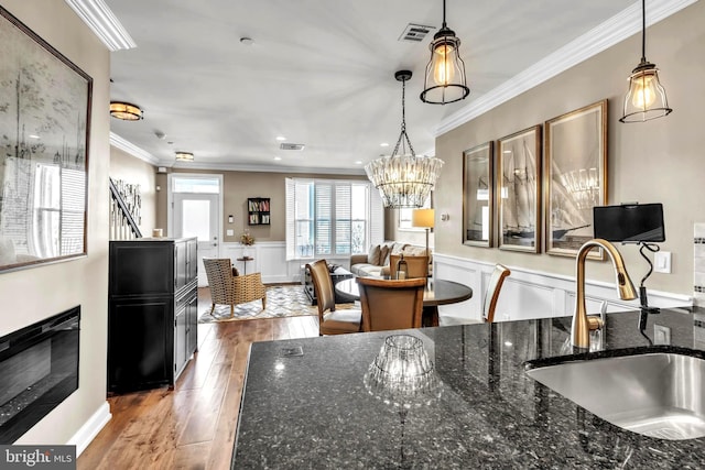 kitchen featuring hardwood / wood-style floors, dark stone counters, sink, and hanging light fixtures