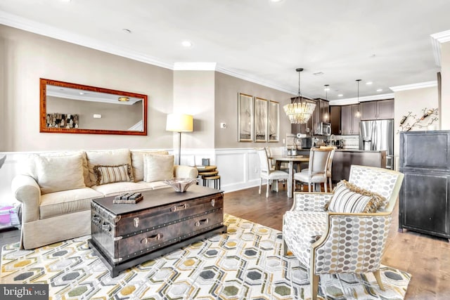 living room featuring ornamental molding, a chandelier, and light hardwood / wood-style floors