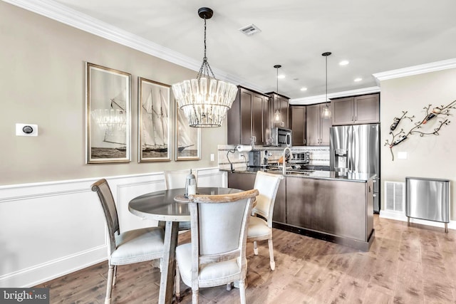 dining space featuring light hardwood / wood-style flooring, ornamental molding, and a chandelier